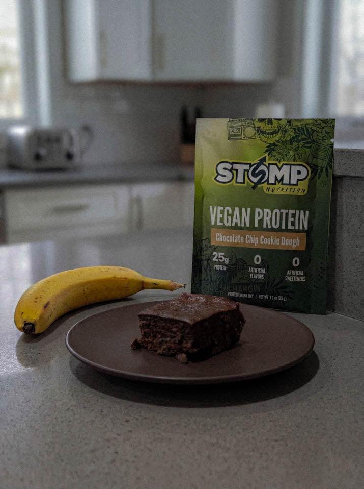 chocolate brownie on kitchen counter with banana and pouch of stomp vegan protein